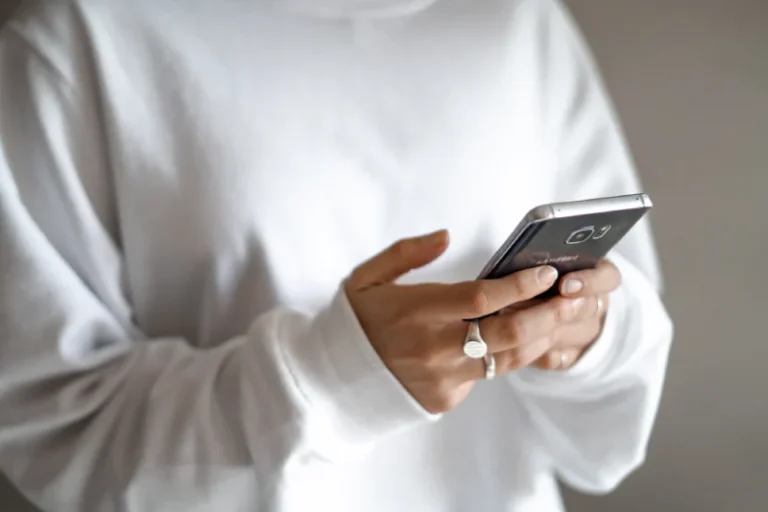 Close-up of a person's hands holding a phone. How to manifest a phone call.