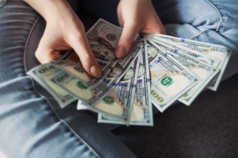 Close-up of a person's hands holding currency, learning how to manifest money.