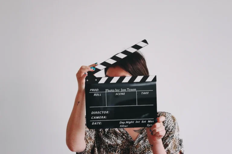 Lady holding up a clapperboard hiding her face. How to manifest being an actress