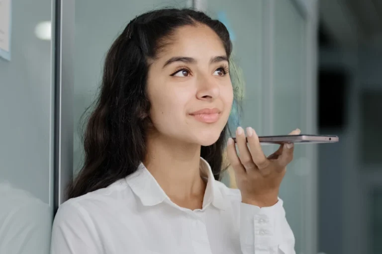 A young woman holding a phone up to her mouth, representing the ability to record your own affirmations audio.